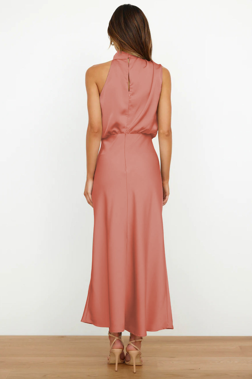 Abito lungo rosa in raso, senza maniche, con scollo alto e schiena scoperta. Elegante e adatto per eventi formali.