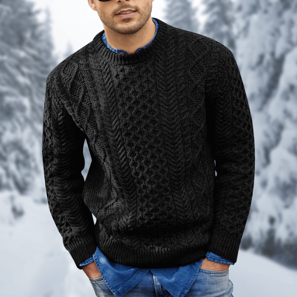 Maglione nero a trecce da uomo, indossato sopra camicia di jeans, sfondo invernale con alberi innevati. Moda invernale, abbigliamento casual elegante.