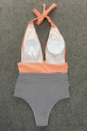 Costume intero donna a righe bianche e nere, con scollo all'americana e fascia arancione. Elegante e moderno, perfetto per la spiaggia.