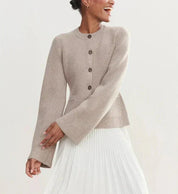 Donna che indossa cardigan beige con bottoni e gonna plissettata bianca. Moda autunnale elegante, abbigliamento casual chic, tendenze 2023.