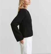Giacca nera donna elegante, maniche lunghe, abbinata a pantaloni bianchi. Moda femminile autunno, stile casual chic.