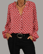 Camicia donna rossa a fantasia geometrica, maniche lunghe, scollo a V, abbinata a pantaloni neri e cintura con fibbia rotonda.