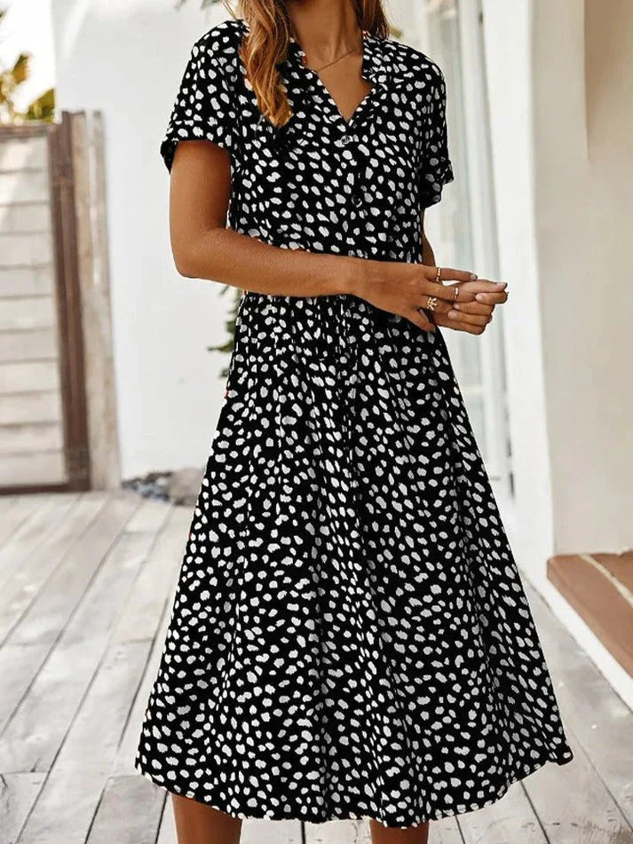 Abito estivo donna nero a pois bianchi, maniche corte, scollo a V, lunghezza media. Moda casual elegante, perfetto per giornate estive.
