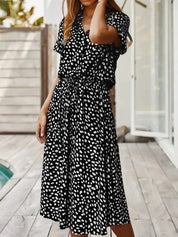 Abito lungo nero a pois bianchi, maniche corte, scollo a V, perfetto per l'estate. Moda donna casual elegante, ideale per eventi all'aperto.