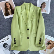 Blazer verde lime elegante su sfondo grigio, circondato da riviste di moda. Giacca donna, stile moderno, bottoni neri, tendenza autunno.