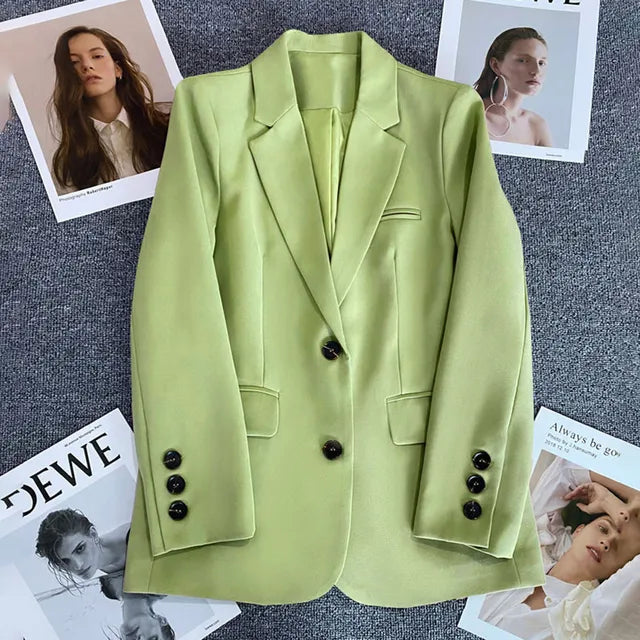 Blazer verde lime elegante su sfondo grigio, circondato da riviste di moda. Giacca donna, stile moderno, bottoni neri, tendenza autunno.
