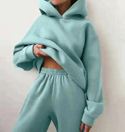Donna in tuta sportiva verde menta, felpa con cappuccio e pantaloni comodi. Abbigliamento casual, moda donna, stile rilassato.