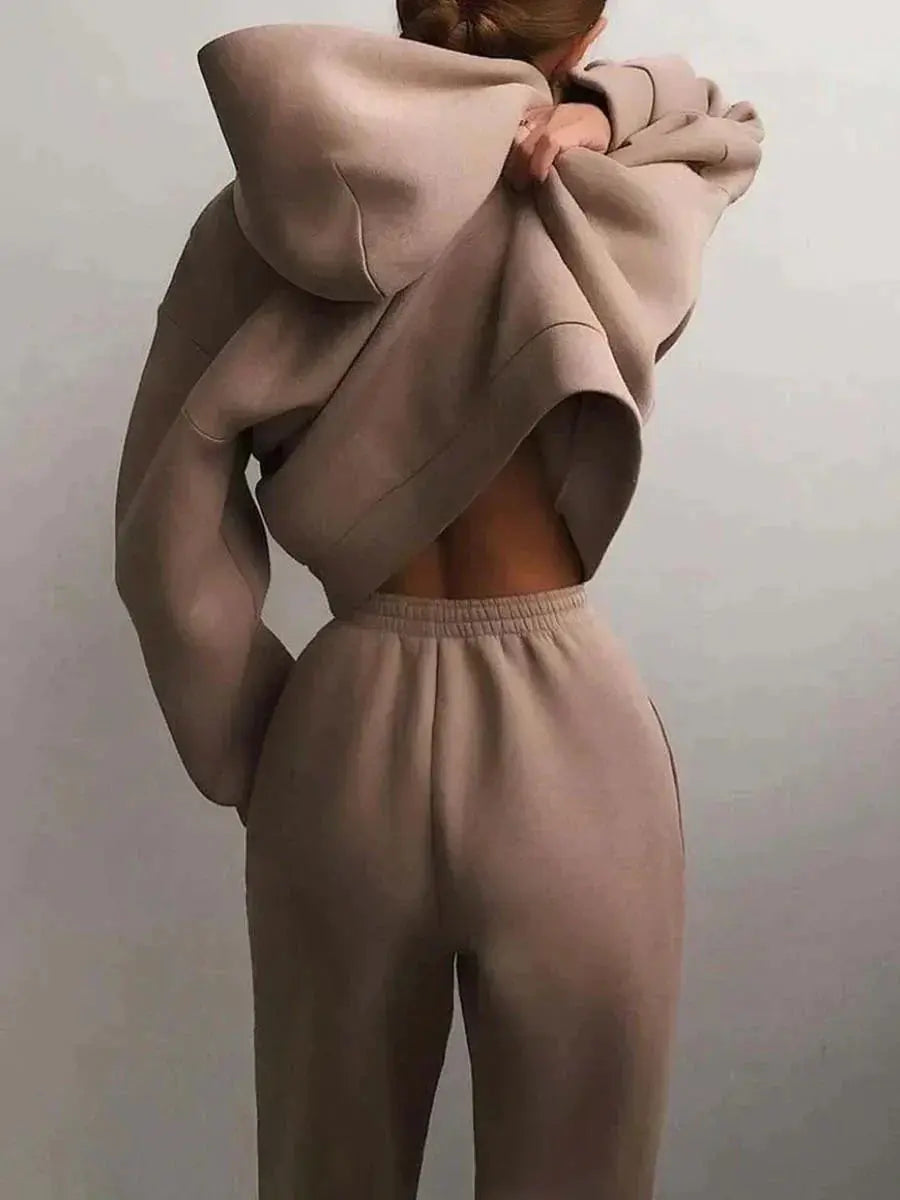 Donna in tuta beige, felpa con cappuccio e pantaloni morbidi, stile casual e confortevole, moda autunnale, abbigliamento sportivo elegante.