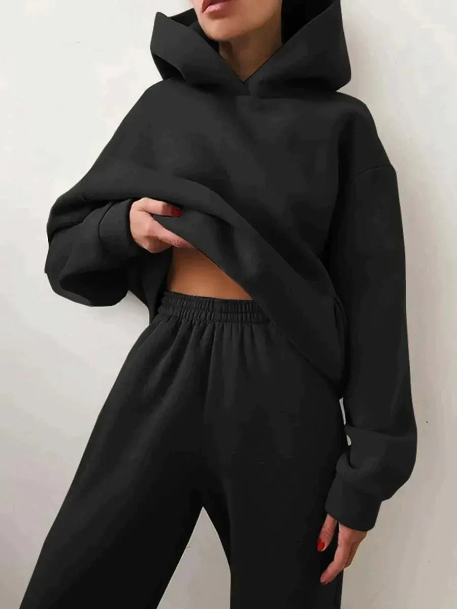 Donna con felpa nera oversize e pantaloni coordinati, moda casual, abbigliamento comodo, stile streetwear, tendenza autunno inverno.