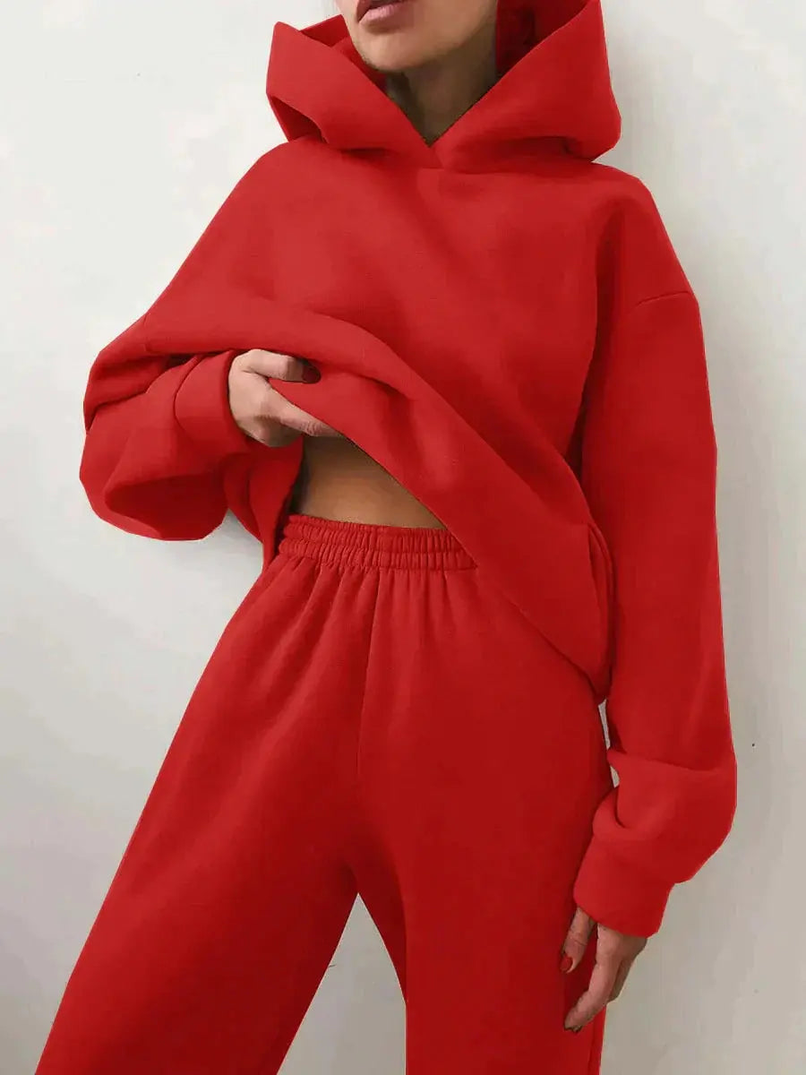 Donna con felpa rossa con cappuccio e pantaloni abbinati, moda casual, abbigliamento sportivo, stile urbano, tendenza autunno inverno.