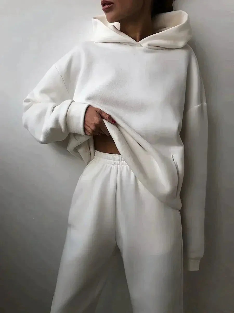 Donna con felpa bianca oversize e pantaloni coordinati, moda casual minimalista, abbigliamento comodo, stile streetwear moderno.
