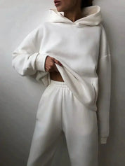 Donna con felpa bianca oversize e pantaloni coordinati, moda casual minimalista, abbigliamento comodo, stile streetwear moderno.