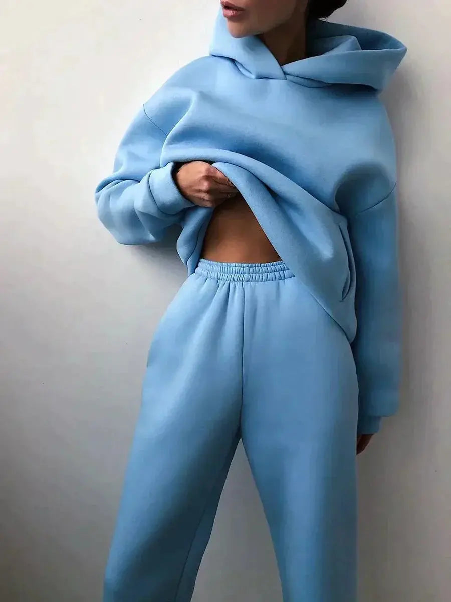 Donna in tuta sportiva azzurra, felpa con cappuccio e pantaloni comodi. Abbigliamento casual, moda donna, stile rilassato.