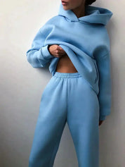 Donna in tuta sportiva azzurra, felpa con cappuccio e pantaloni comodi. Abbigliamento casual, moda donna, stile rilassato.