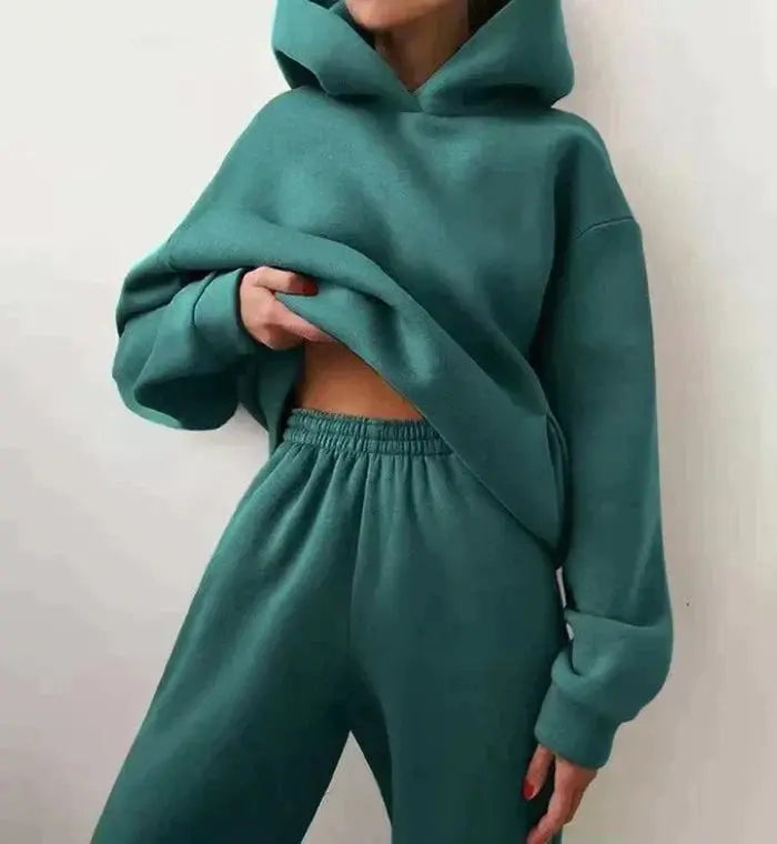 Donna in tuta sportiva verde acqua, felpa con cappuccio e pantaloni larghi. Abbigliamento casual, moda donna, comfort e stile.