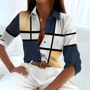 Camicia donna elegante a quadri astratti blu, bianco e oro, maniche lunghe, abbinata a pantaloni bianchi. Moda femminile contemporanea.