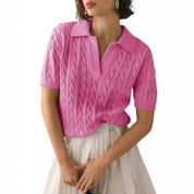 Maglia rosa a maniche corte con motivo a trecce, colletto a polo, indossata da una donna. Elegante e casual, perfetta per la moda estiva.