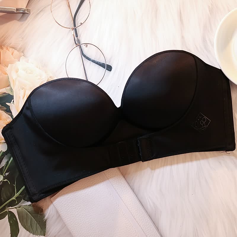 Reggiseno nero senza spalline su sfondo bianco, accanto a occhiali e fiori. Intimo femminile elegante, ideale per abiti scollati.
