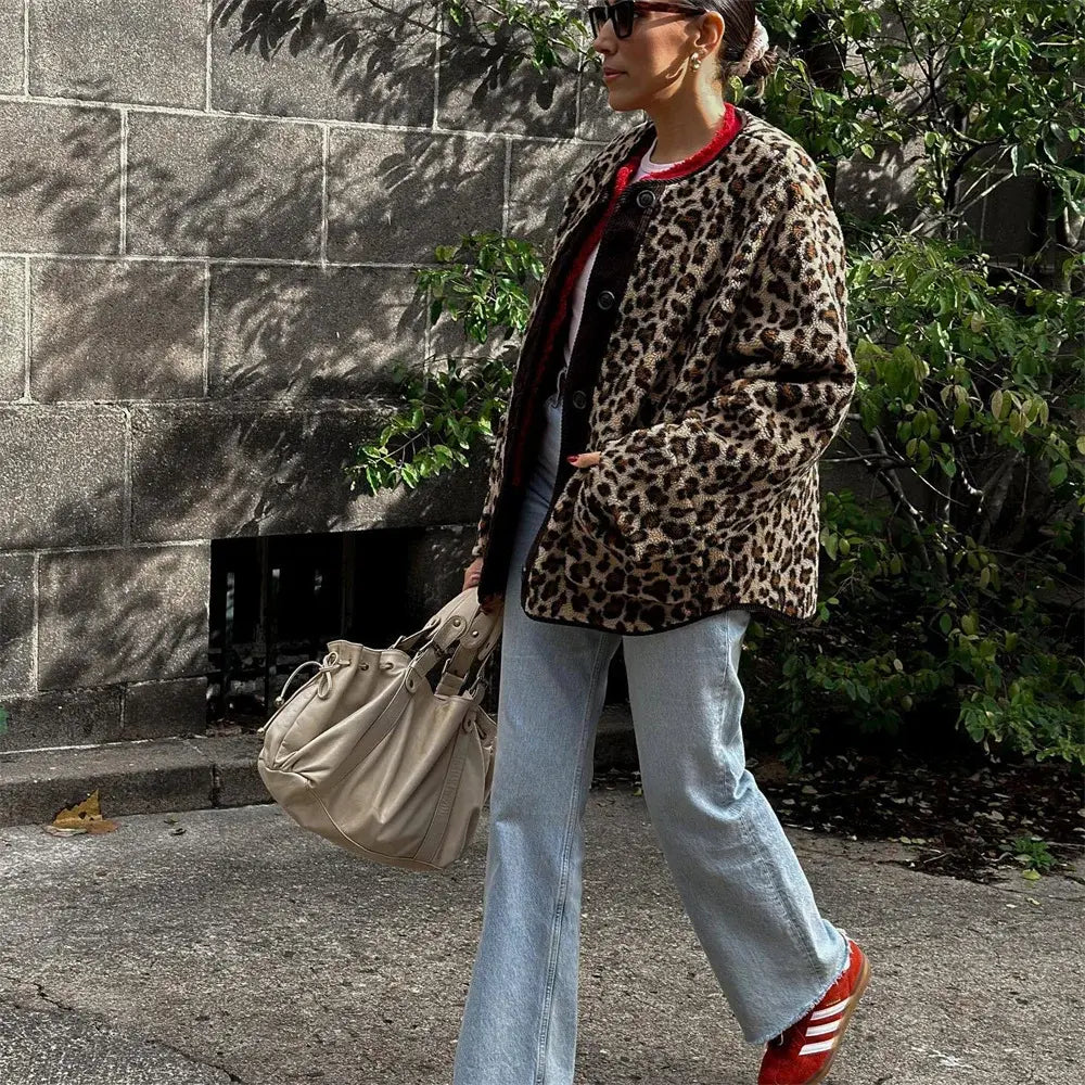 Donna con cappotto leopardato, jeans a zampa, borsa beige e scarpe rosse. Moda autunnale, stile urbano, tendenze abbigliamento donna.
