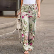 Pantaloni larghi donna floreali, vita alta con laccio, tessuto leggero, perfetti per estate, moda casual, abbinati a top bianco e borsa beige.