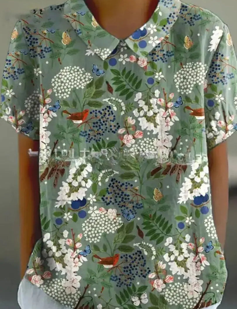 Camicia donna a maniche corte con stampa floreale verde, colletto classico, farfalle e fiori colorati. Moda estiva casual elegante.