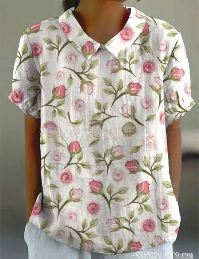 Camicia donna a maniche corte con stampa floreale rosa su sfondo bianco, colletto classico. Elegante e casual, perfetta per la primavera.