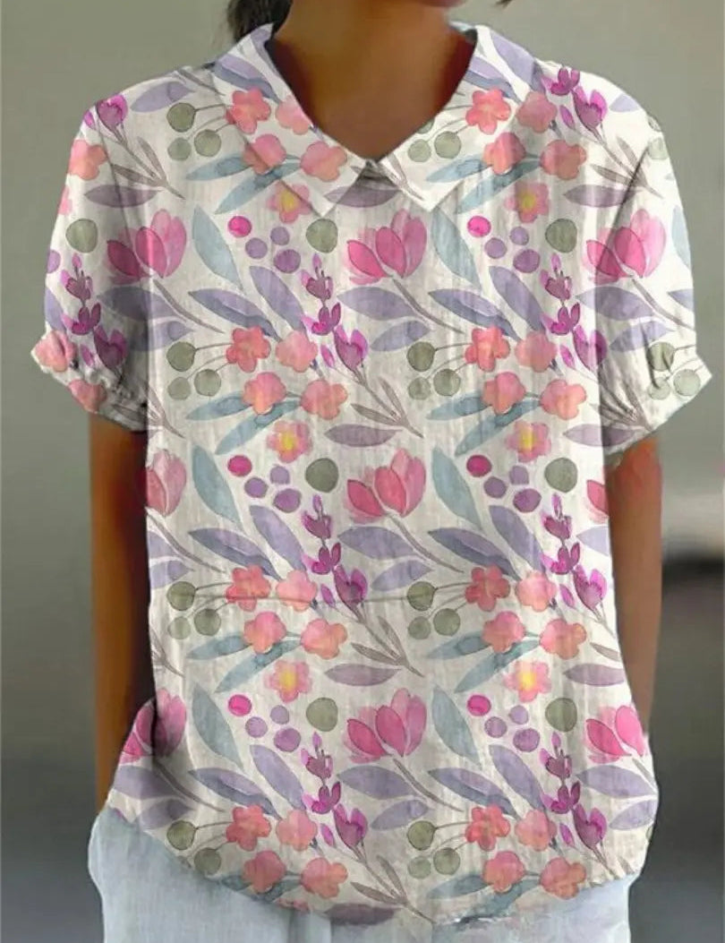 Camicia donna a maniche corte con colletto, motivo floreale colorato su sfondo bianco, stile casual estivo, tessuto leggero e traspirante.