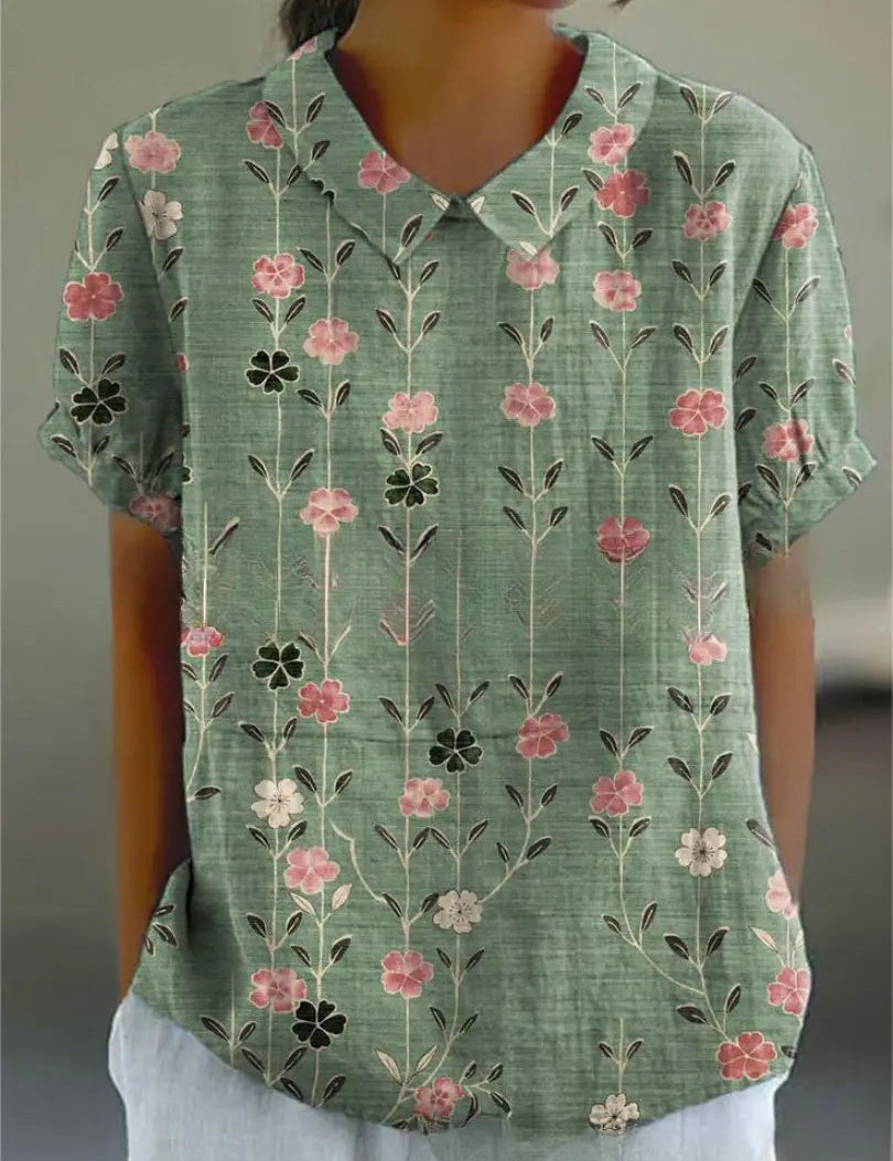 Camicia donna verde con stampa floreale rosa e bianca, maniche corte, colletto classico. Moda estiva casual, tessuto leggero e traspirante.