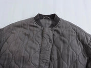 Giacca trapuntata grigia con bottoni a pressione, colletto a coste, design ondulato. Moda autunnale, abbigliamento casual, stile moderno.