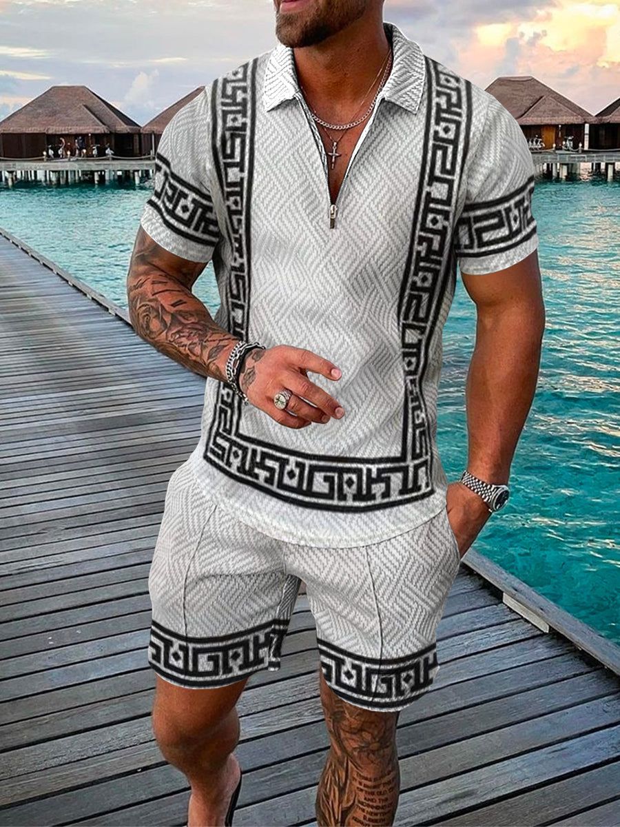 Uomo in completo estivo bianco e nero con motivo geometrico, su passerella di legno vicino al mare. Abbigliamento casual elegante per vacanze.