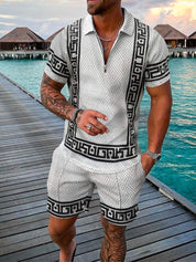 Uomo in completo estivo bianco e nero con motivo geometrico, su passerella di legno vicino al mare. Abbigliamento casual elegante per vacanze.