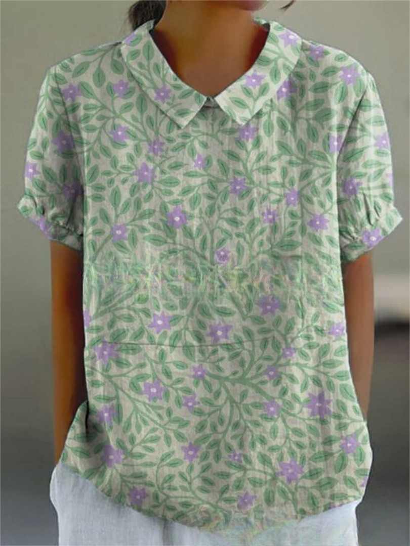 Camicia donna a maniche corte con colletto, motivo floreale verde e viola, tessuto leggero, ideale per estate, moda casual femminile.