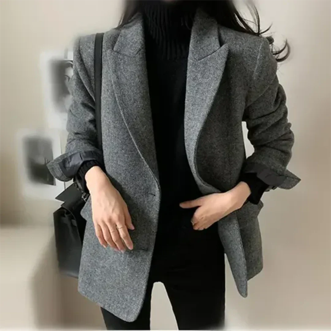 Giacca donna elegante grigia, stile casual chic, abbinata a maglione nero. Moda autunnale, outfit versatile per ufficio o eventi formali.