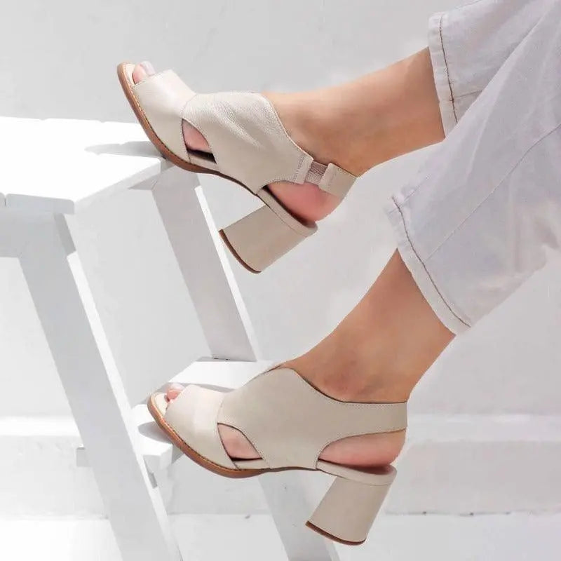 Sandali donna beige con tacco largo, design aperto, indossati su scala bianca. Scarpe estive eleganti, comode e alla moda.