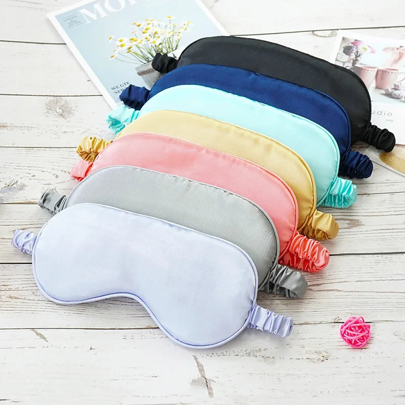 Mascherine per dormire in seta multicolore su tavolo di legno. Accessori per il sonno, comfort, relax. Ideali per viaggi e riposo notturno.