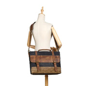 Borsa messenger in tela cerata e pelle marrone su manichino, stile vintage, tracolla regolabile, ideale per lavoro e viaggio.