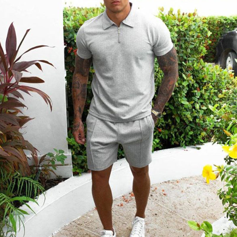 Uomo in completo estivo grigio, polo e pantaloncini, in giardino. Look casual elegante, moda maschile, abbigliamento estivo, stile moderno.