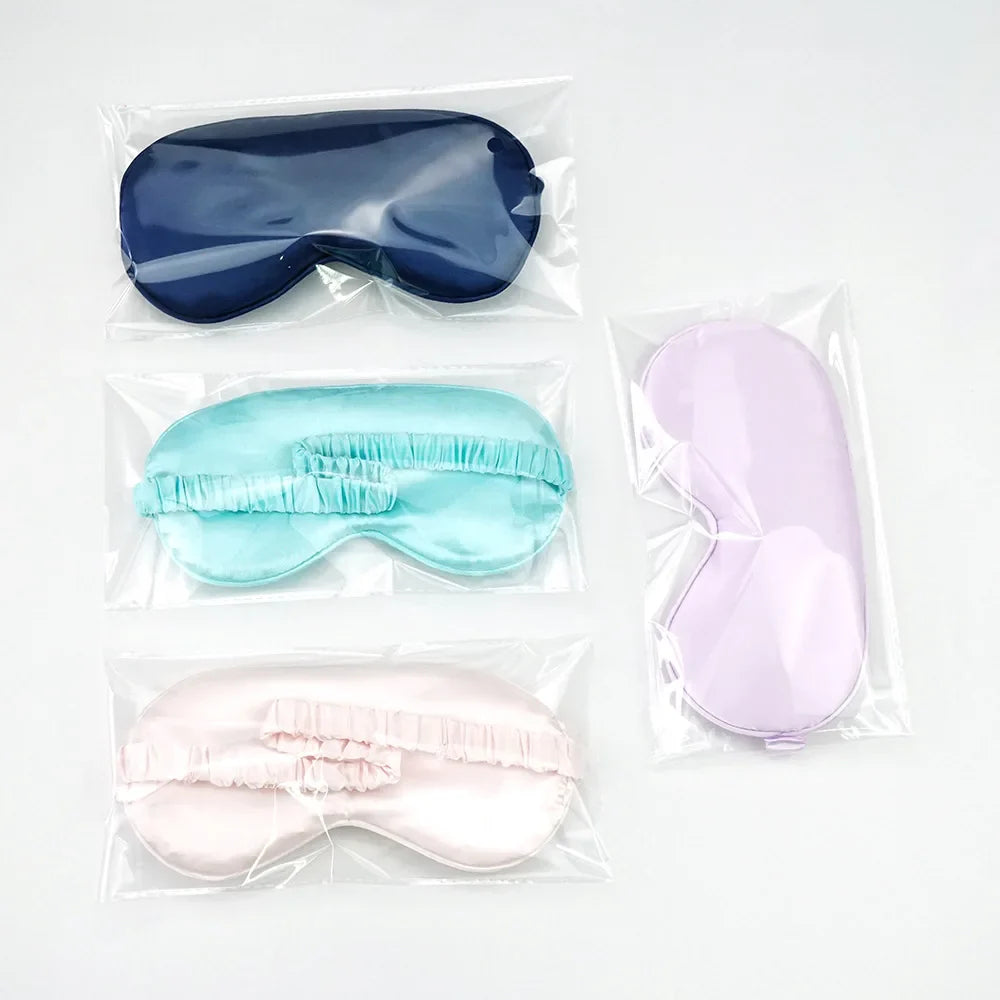 Quattro maschere per dormire in raso, colori blu, turchese, rosa e lilla, confezionate singolarmente. Accessori per il sonno, comfort e relax.