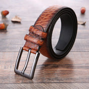 Cintura in pelle marrone con fibbia in metallo su sfondo di legno, design elegante e texture a scaglie, accessorio moda uomo.
