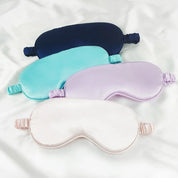 Quattro mascherine per dormire in seta, colori blu, turchese, lilla e bianco, su sfondo bianco. Accessori per il sonno, comfort, relax.