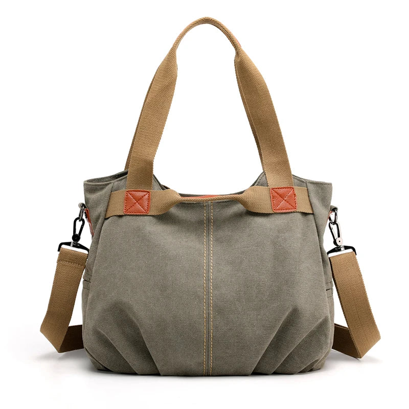 Borsa a tracolla in tela verde oliva con manici marroni, dettagli in pelle, e tracolla regolabile. Design casual e spazioso per uso quotidiano.