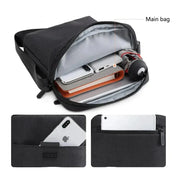 Borsa a tracolla nera con scomparto principale aperto, contenente smartphone, power bank e accessori. Tasche esterne per dispositivi elettronici.