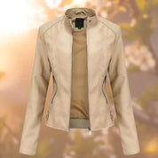 Giacca in pelle beige da donna con zip, design elegante e moderno, perfetta per la moda autunnale. Sfondo sfocato con luce solare.
