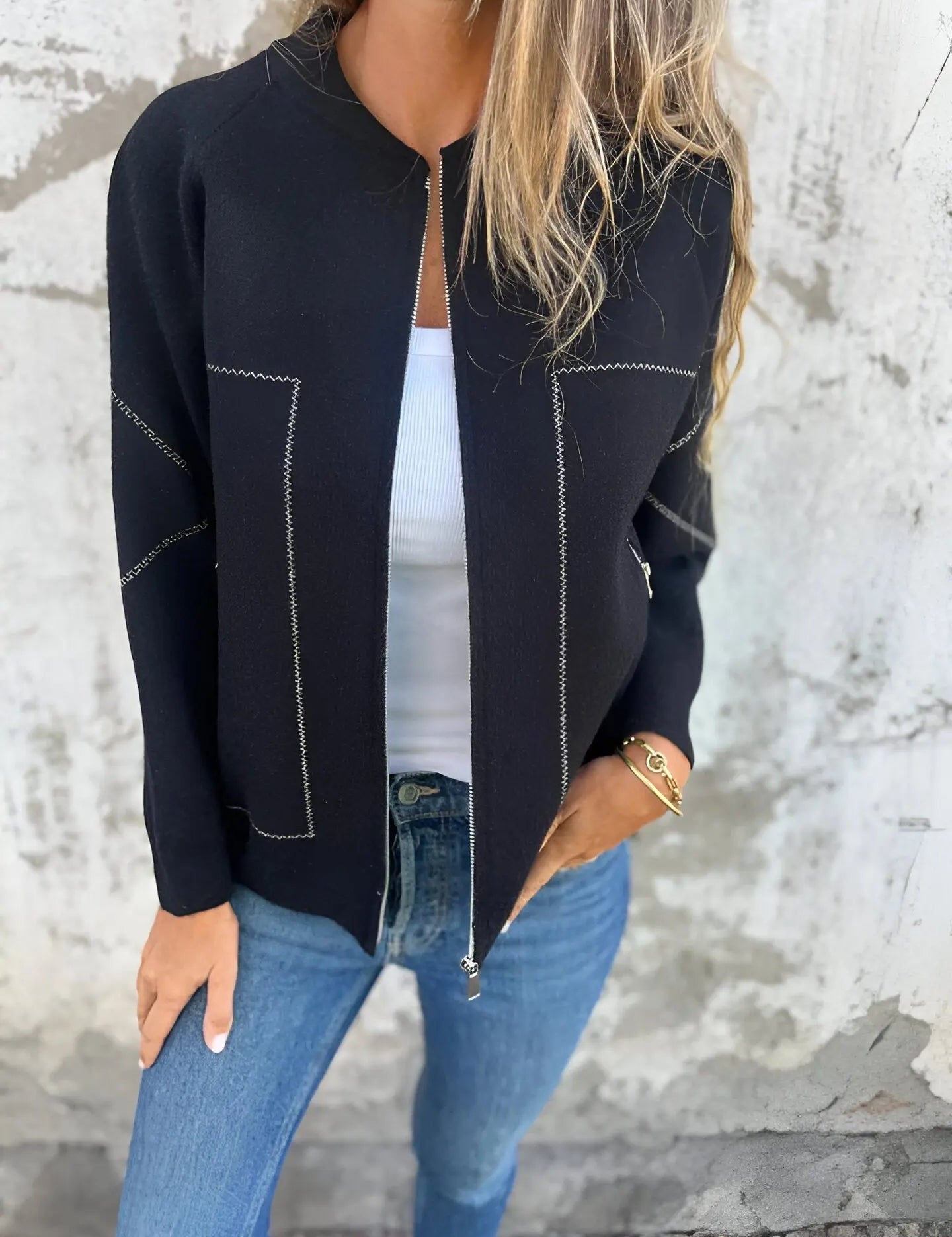 Giacca nera elegante con cuciture bianche, indossata su top bianco e jeans blu. Moda donna casual chic, abbigliamento autunnale trendy.