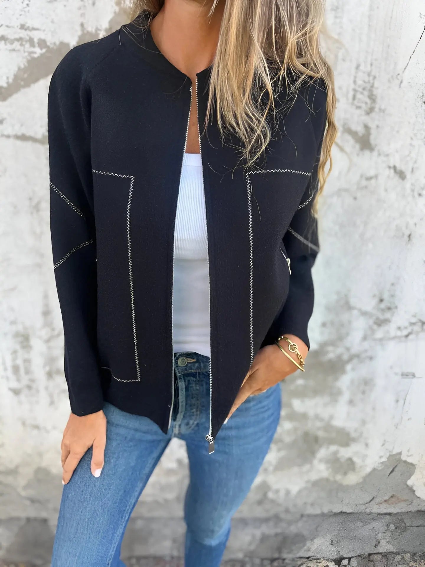 Giacca nera elegante con cuciture bianche, indossata su top bianco e jeans blu. Moda donna casual chic, abbigliamento autunnale trendy.