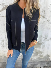Giacca nera elegante con cuciture bianche, indossata su top bianco e jeans blu. Moda donna casual chic, abbigliamento autunnale trendy.