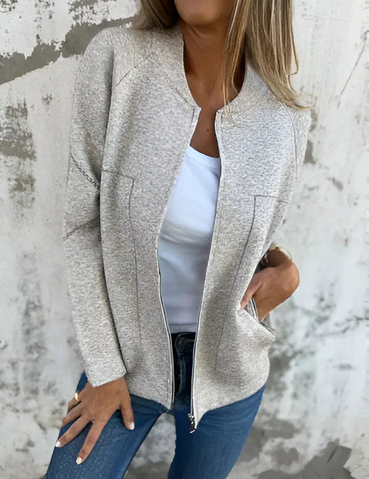 Giacca donna beige in tessuto morbido, con zip frontale, indossata su maglietta bianca e jeans. Look casual chic, moda autunnale.
