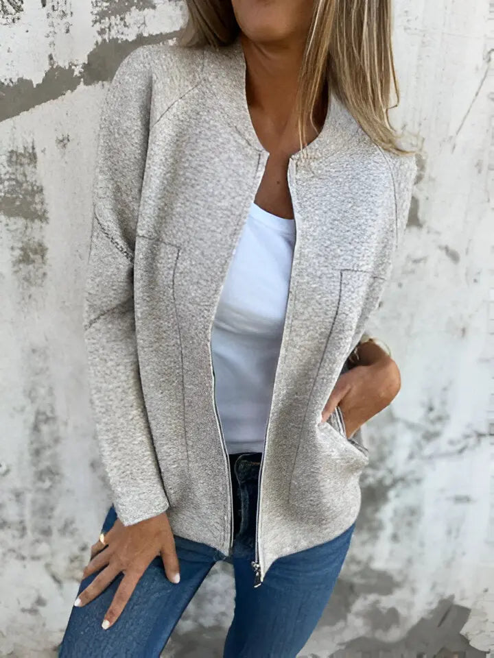 Giacca donna beige in tessuto morbido, con zip frontale, indossata su maglietta bianca e jeans. Look casual chic, moda autunnale.
