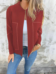 Giacca rossa donna, zip frontale, dettagli cuciture bianche, indossata con jeans blu e top bianco. Moda casual autunnale, stile urbano.