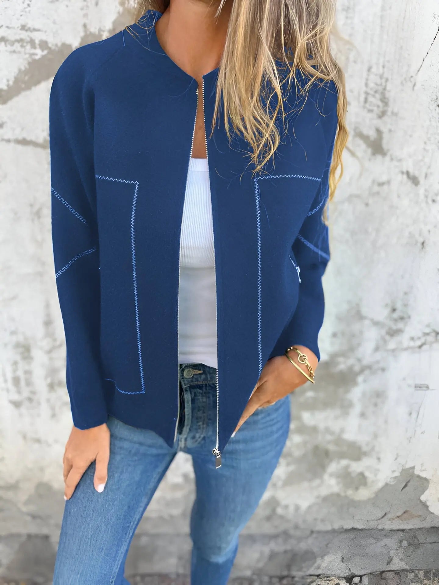 Giacca blu donna, zip frontale, indossata con jeans e top bianco. Moda casual autunnale, stile elegante e moderno.